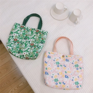 Détail des sacs repas en coton fleuri avec fermeture à bouton sur fond blanc
