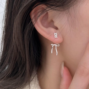 Elegant 925 sterling silver bow earrings and cross studs set on a female model