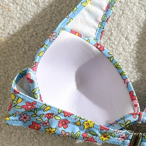 Détail du haut de bikini à fleurs bleues avec coussinets blancs moulés sur fond en peluche