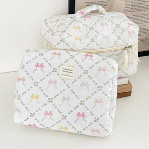 Détail du motif floral à nœuds sur trousse de maquillage matelassée et sa pochette