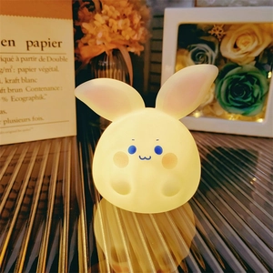 Detail shot of a cute rabbit night light emitting soft warm yellow glow on a nightstand