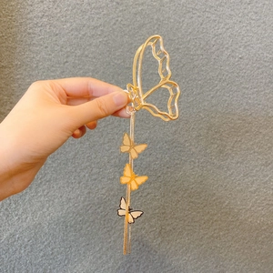 Detail of golden metal butterfly hair claw clip with long tassels and small butterfly charms