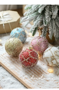 Macro shot of 8cm glitter and pearl foam Christmas balls on a snowy tray with pine branches