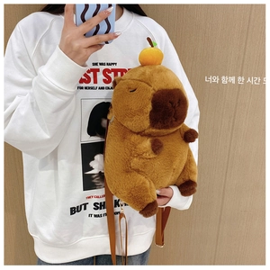 Detail of plush capybara backpack with orange decor and adjustable metal straps