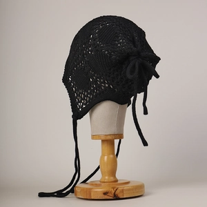 Détail de bonnet en crochet noir fait main avec motifs floraux ajourés et lacets