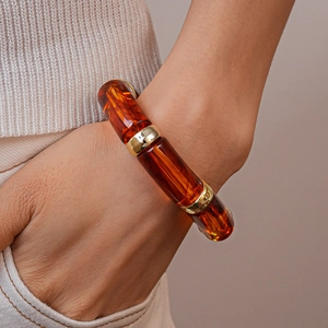 Close-up of amber resin bamboo-style bracelet with gold metal links on a wrist