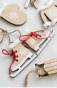 Macro detail of wooden Christmas ornaments featuring skates and sleds with faux fur and laces