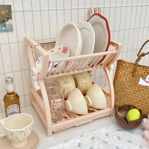 Pink double-tier kitchen dish drying rack for plates and cutlery in a cozy setting