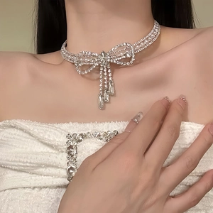 Detailansicht der Schleifen-Halskette mit Strass-Quasten und Perlen an einem Model