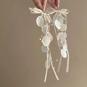 Detail of elegant bow pearl tassel earrings with silk ribbons and translucent beads