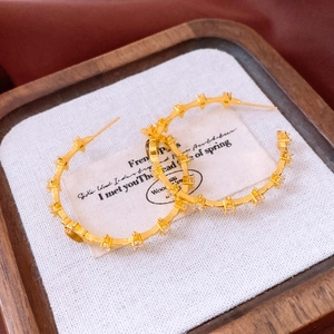 Macro view of 18k gold star hoop earrings with tiger eye and brown gems on wood