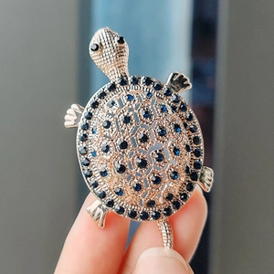 Detail shot of a sea turtle brooch with blue rhinestones and a gold-plated alloy finish