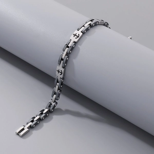 Detailed view of stainless steel anchor bracelet with black links on a gray stand