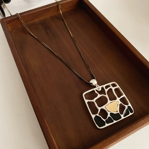 Détail du pendentif géométrique carré avec incrustation sur chaîne à double couche