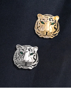 Close-up of tiger head brooches in gold and silver with rhinestones on velvet