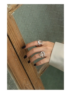 Detailed view of silver chain link and cross knot rings on model hands with black nails