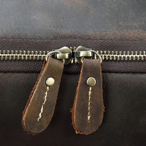 Detail of vintage copper dual zippers and hand-stitched leather pullers on brown crazy horse bag