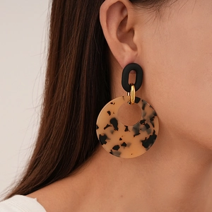 Detail of resin leopard print hoop earring with gold metal link on female model