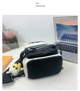 Détail d'un sac bandoulière noir et blanc avec pendentif en peluche et boucle solide