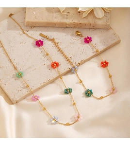 Close-up of 18K gold plated chains with colorful crystal flowers on silk and slate