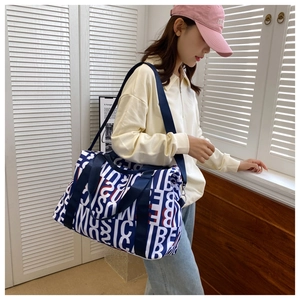 Blue and white canvas travel bag with letter print shown on a crossbody model