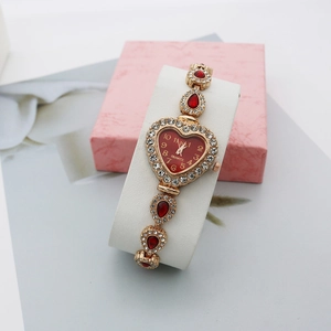 Détail de la montre coeur dorée avec gemmes gouttes rouges et lunette en cristal