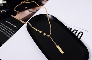 Detailed close-up of 18K gold plated bar pendant on a coffee bean chain necklace