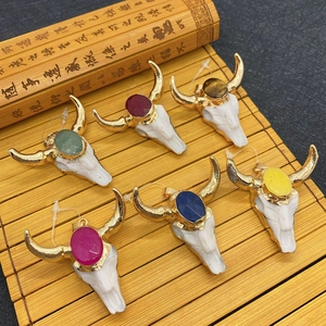 Colorful natural stone ox head skull pendants with golden horns on bamboo background