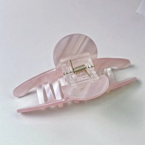 Detail shot of pink acetate hair claw clip with pearlescent finish and gold spring