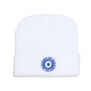 Detailed embroidery of Blue Evil Eye and No Bad Vibes text on a white knit beanie