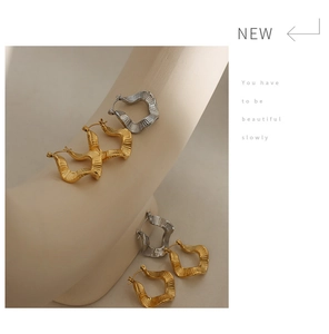 Macro view of irregular wavy textured hoop earrings in gold and silver plating