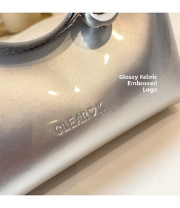Detailed close-up of glitter silver fabric texture and CLEAR K embossed logo on handbag