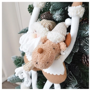 Plush Santa and reindeer ornaments hanging on a Christmas tree with cozy warm tones