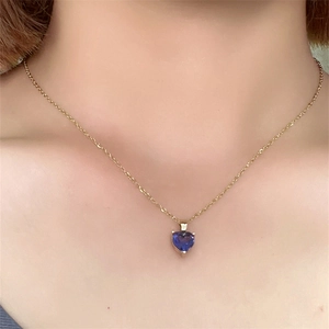 Detail of heart-shaped blue zircon pendant necklace on neck with gold plated titanium chain
