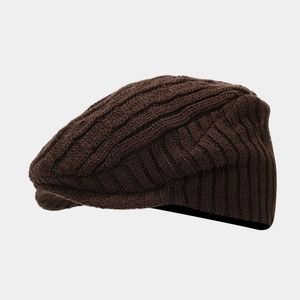 Close-up of brown cable knit beret hat featuring thick yarn texture and short brim