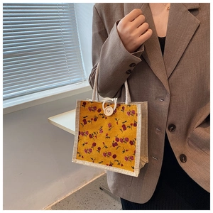 Close-up of a floral mini handbag with a wood button and cotton rope handles on a model