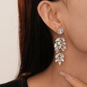 Boucles d'oreilles pendantes feuilles argentées avec strass portées par un mannequin