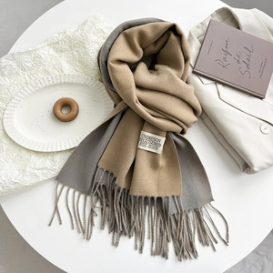 Macro detail of camel and grey dual-tone cashmere-style scarf with woven label and fringe