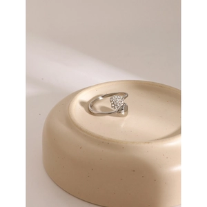 Detailed view of an open silver stainless steel ring with a pave-set heart and crystals