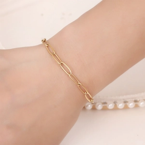 Waterproof gold paperclip chain bracelet on wrist with elegant pearl accents background