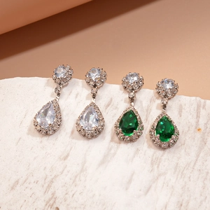 Close-up of pear-cut green and white zircon teardrop earrings on white stone props