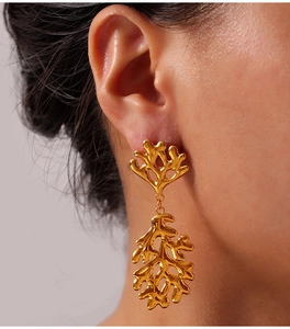 Detail of gold coral-shaped earrings with mirror finish on model ear with grey background