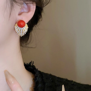 Detail view of fan-shaped earring with red pearl and sparkling zircon on a model