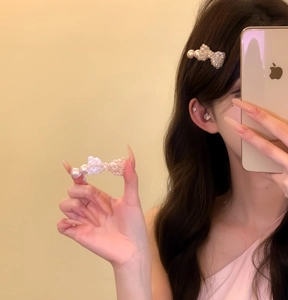 Detailed view of an elegant pearl bow duckbill hair clip worn by a model in a mirror selfie
