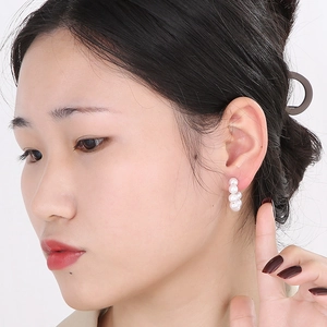 Close-up of C-shaped 18K gold plated hoop earrings with five round white pearls on model