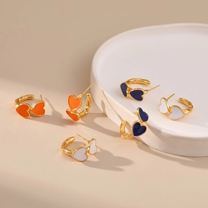 Detail of colorful enamel heart-shaped C-style hoop earrings on a ceramic dish