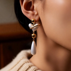 Detail showing vintage gold heart earrings with drop pearls on model's ear