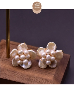 Detailed macro shot of baroque pearl flower stud earrings on a dark walnut wood base