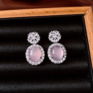 Detailed macro view of vintage oval pink gemstone earrings with zircon flower accents