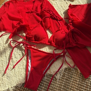 Set bikini rosso tre pezzi con copricostume traforato a maniche lunghe e tessuto testurizzato